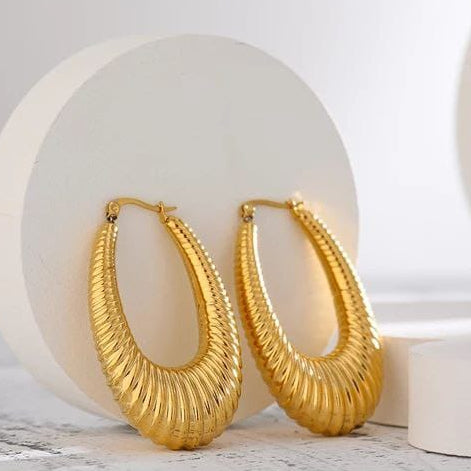 Gold hoop earrings on a white surface with a light gray background