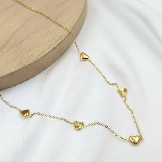 Gold necklace with heart-shaped pendants on a white background