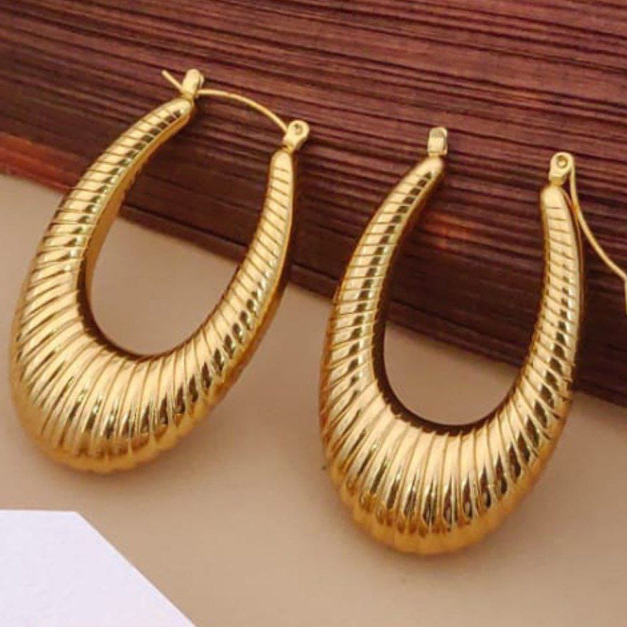 Gold hoop earrings on a wooden surface