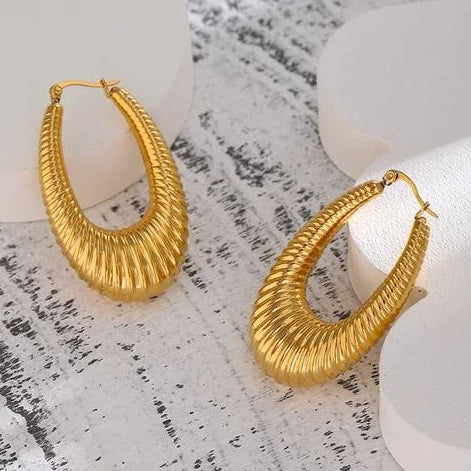 Gold hoop earrings on a textured white surface