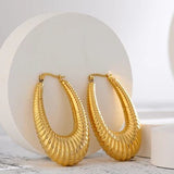 Gold hoop earrings on a white surface with a light gray background