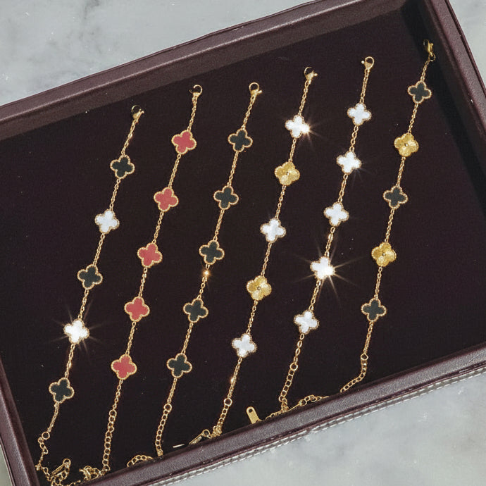 Set of 18K gold plated, anti tarnish necklaces with floral clover designs on a maroon tray